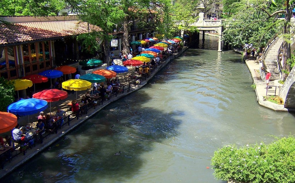 People enjoying a meal while sitting on chairs along side River Walk San Antonio advertising agency.