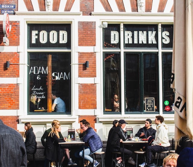 People sitting on chairs outside a restaurant in a street, Amsterdam restaurant advertising agency