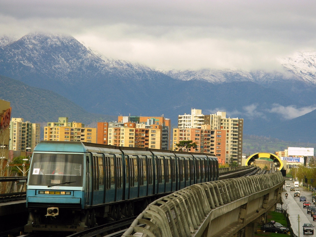 Metro train on an elevated portion with a snow-capped mountain(behind), Santiago advertising agency.