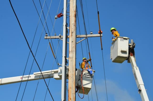 Two electricians fixing high voltage lanes, Electrician Advertising Agency.