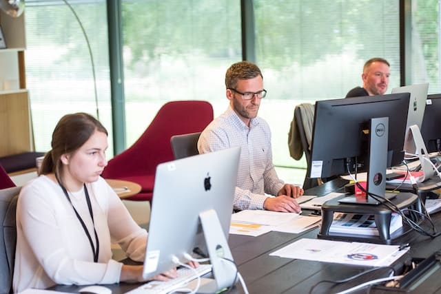 Financial analysts on their respective desks, Bank & Finance Advertising Agency.