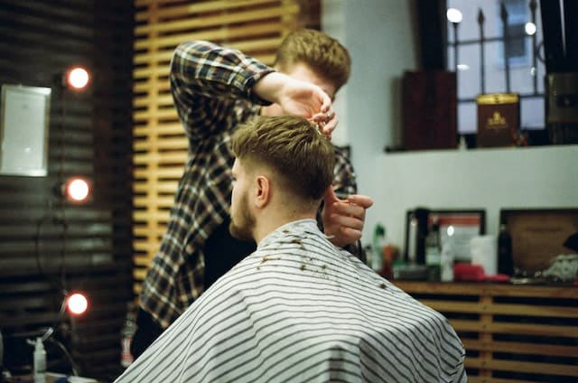 A hairstylist cutting hair of a client, Hair Salon Advertising Agency.