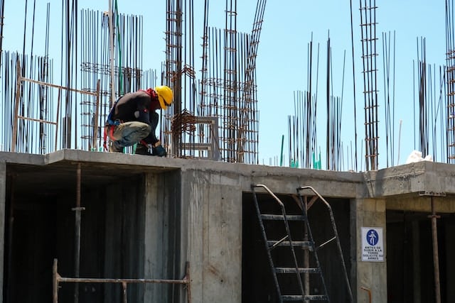 A worker fixing metal rods on roof, Roofing Advertising Agency.