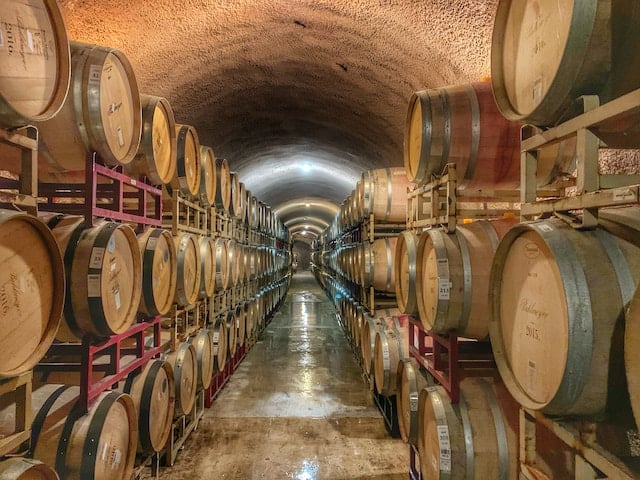 Barrels full of wine in an underground warehouse, Wine Advertising Agency.