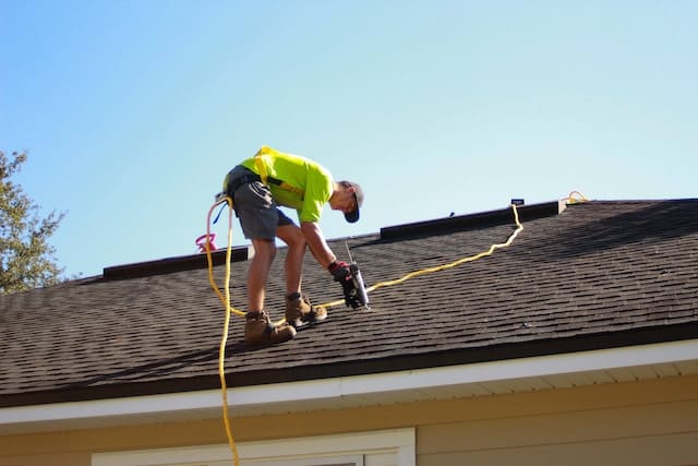 Worker drilling in the roof, Roofing Advertising Agency.