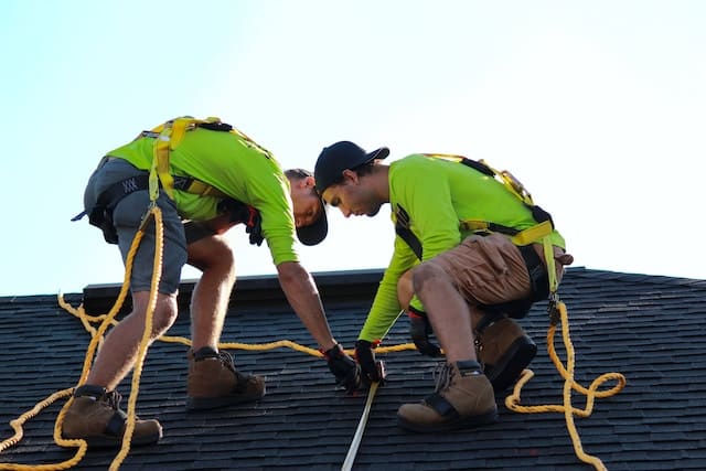 Two workers fixing issues on roof, Roofing Advertising Agency.