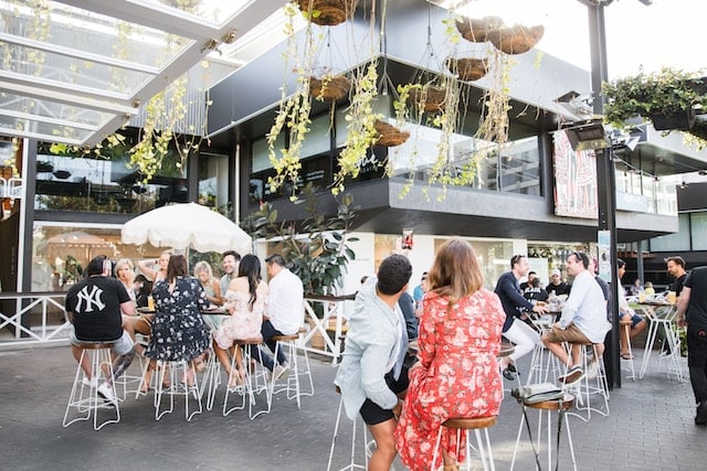 People sitting outside the restaurant enjoying meal with plant pots above, Restaurant Advertising Agency.